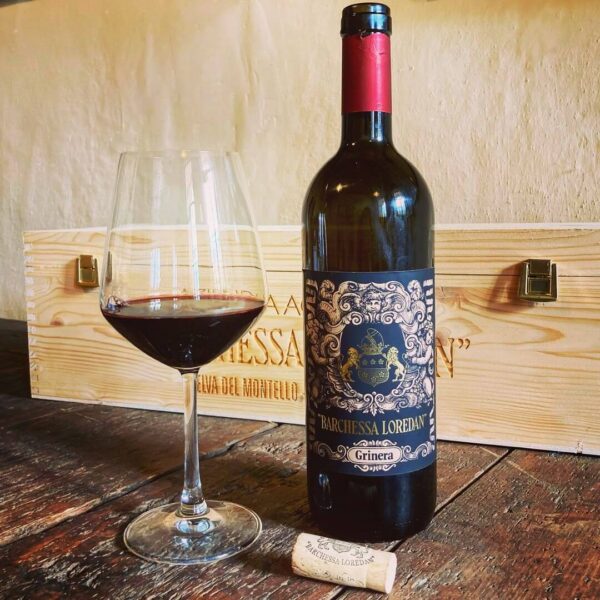 Vino rosso del Montello "Grinera IGT Colli Trevigiani", versato in un calice da degustazione. Sullo sfondo, la confezione in legno firmata Cantina Barchesa Loredan.