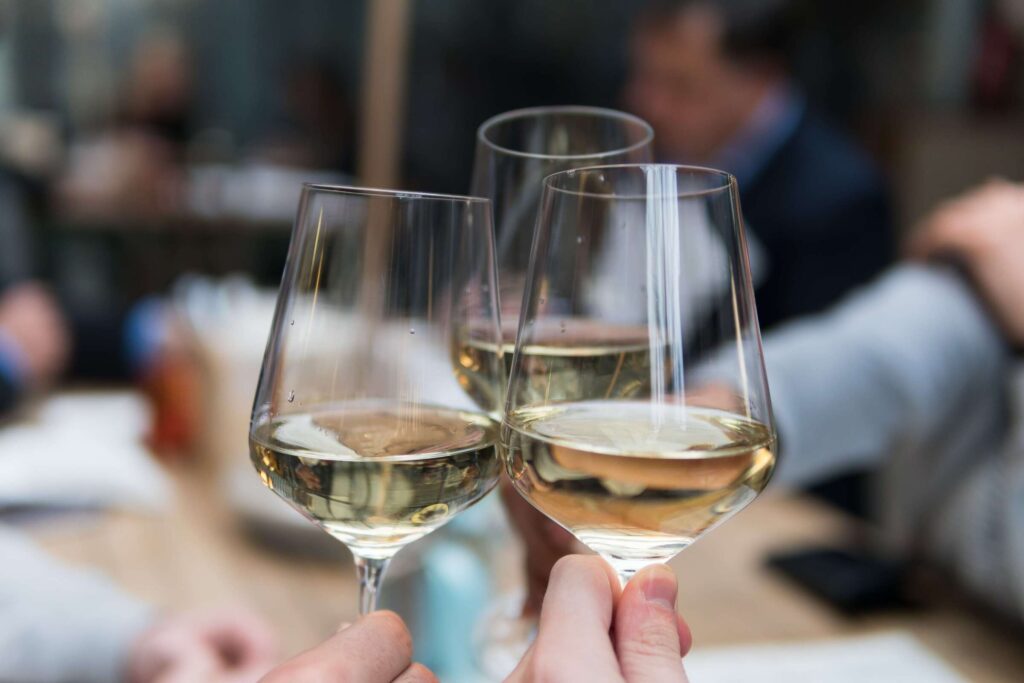 Amici brindano con tre calici di vino bianco Traminer aromatico Selva Bianca di Cantina Barchessa Loredan.